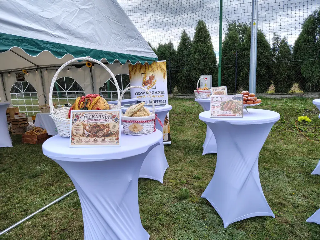 Stoły z lokalnymi produktami przy namiocie podczas pikniku w Rusinowie.