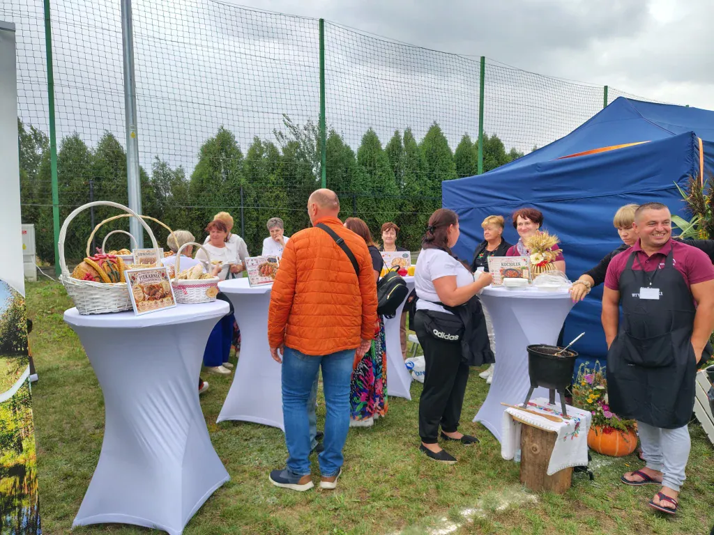 Goście oglądający regionalne produkty na stoiskach pikniku.